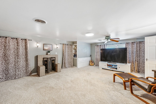 living room featuring light carpet, a tile fireplace, and ceiling fan