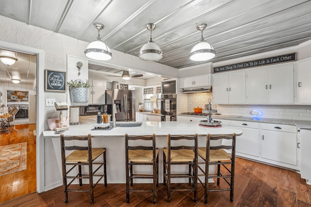 kitchen with a breakfast bar, white cabinets, backsplash, and stainless steel appliances