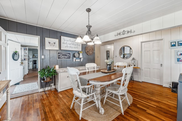 dining space featuring an inviting chandelier, wood walls, and hardwood / wood-style floors