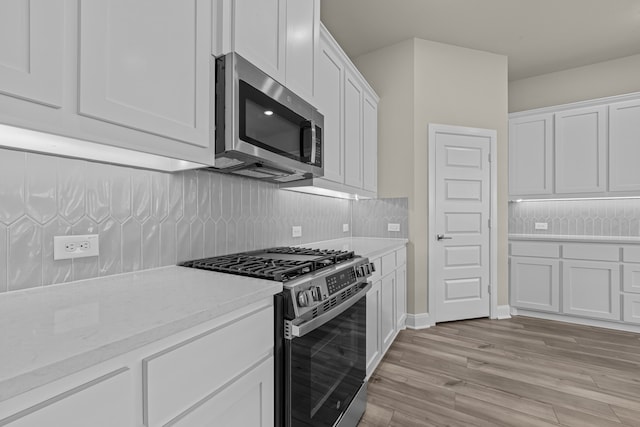 kitchen with white cabinetry, backsplash, light hardwood / wood-style floors, and appliances with stainless steel finishes