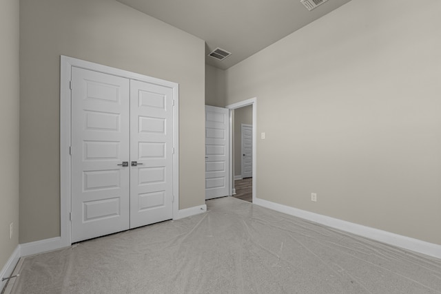 unfurnished bedroom featuring light colored carpet and a closet