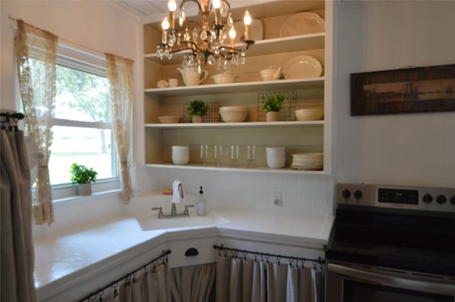 kitchen with plenty of natural light, stainless steel range with electric stovetop, sink, and a chandelier