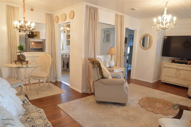 living room with a notable chandelier, dark hardwood / wood-style flooring, and ornamental molding