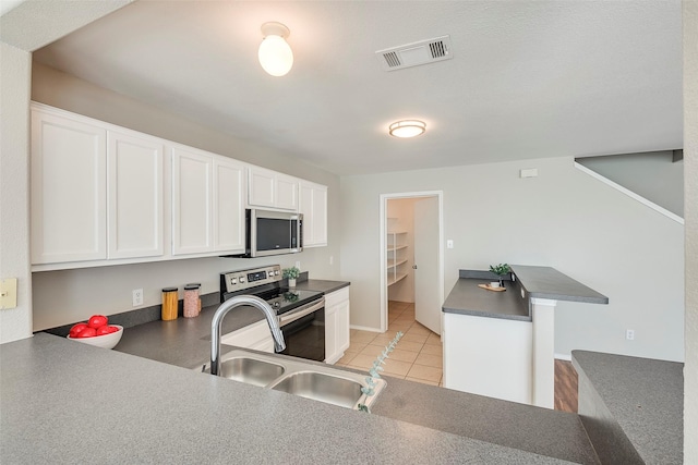 kitchen featuring visible vents, a sink, dark countertops, appliances with stainless steel finishes, and white cabinets