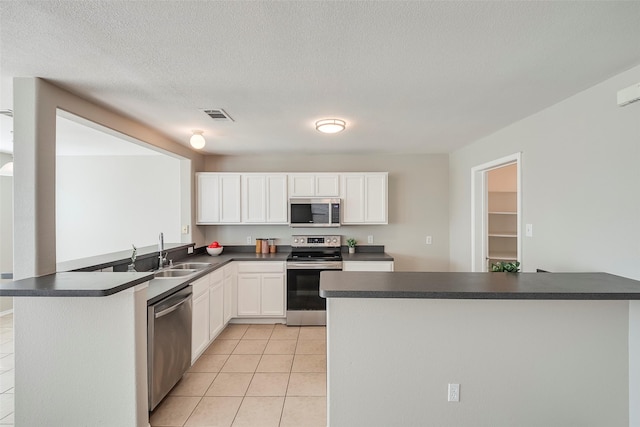 kitchen featuring a sink, stainless steel appliances, dark countertops, and visible vents