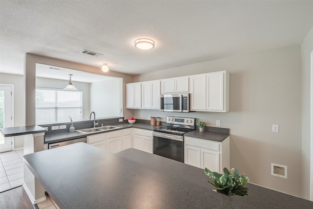 kitchen with stainless steel appliances, sink, hanging light fixtures, light tile patterned floors, and white cabinetry