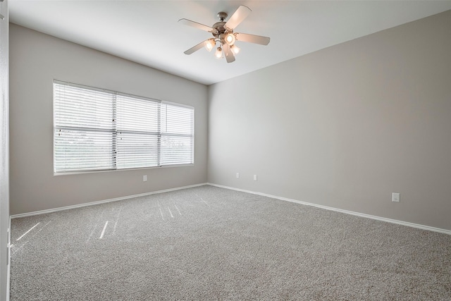 empty room with carpet flooring, a ceiling fan, and baseboards