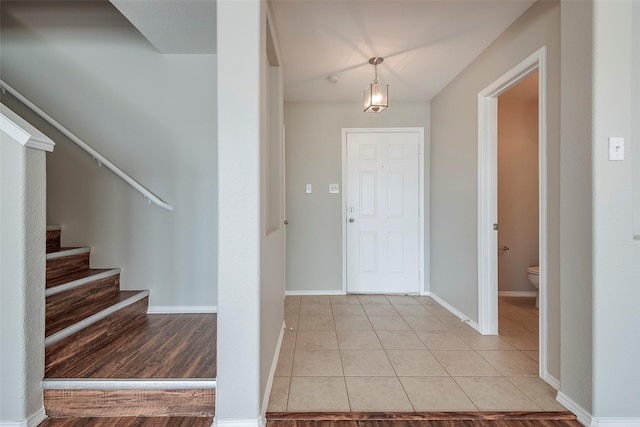 foyer with light tile patterned floors, stairs, and baseboards