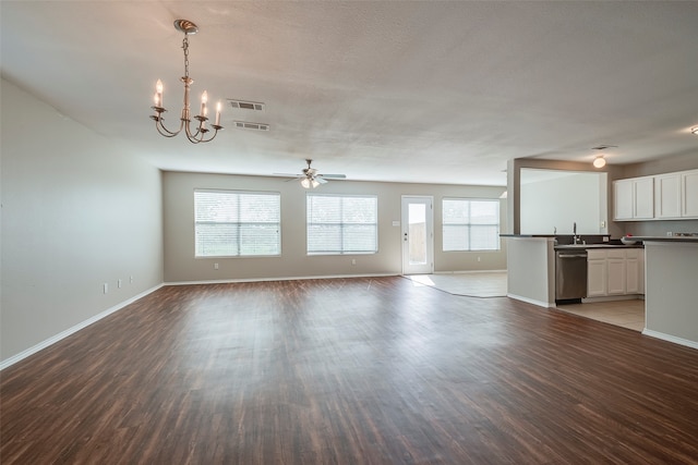 unfurnished living room featuring sink, ceiling fan with notable chandelier, hardwood / wood-style flooring, and a healthy amount of sunlight