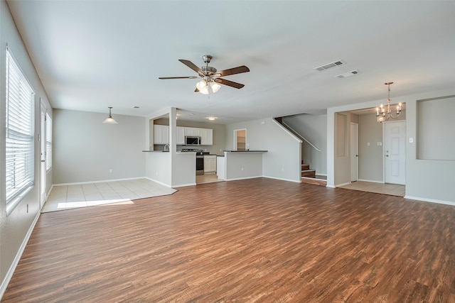 unfurnished living room featuring ceiling fan with notable chandelier, light wood-style floors, and visible vents