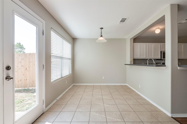 unfurnished dining area featuring light tile patterned floors, visible vents, baseboards, and a sink