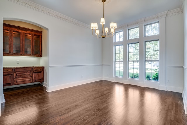 unfurnished dining area with dark wood-type flooring, a chandelier, and ornamental molding