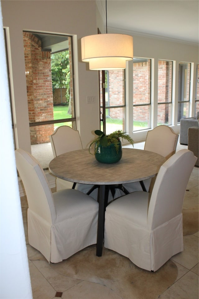 dining space with brick wall, ornamental molding, and light tile patterned floors