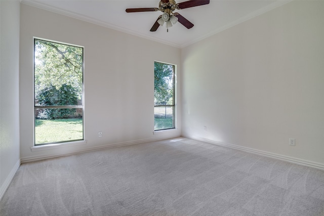 carpeted spare room with a healthy amount of sunlight, ceiling fan, and crown molding