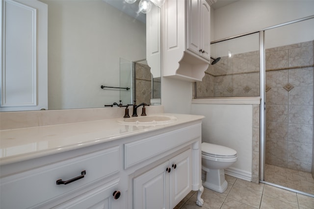 bathroom with a shower with shower door, vanity, tile patterned flooring, and toilet