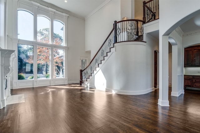 foyer entrance with ornamental molding, wood-type flooring, and a high ceiling