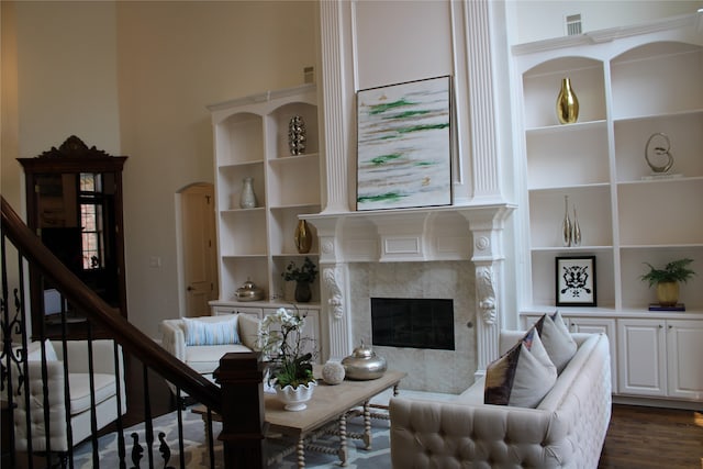 living room with a high end fireplace, dark wood-type flooring, and built in features