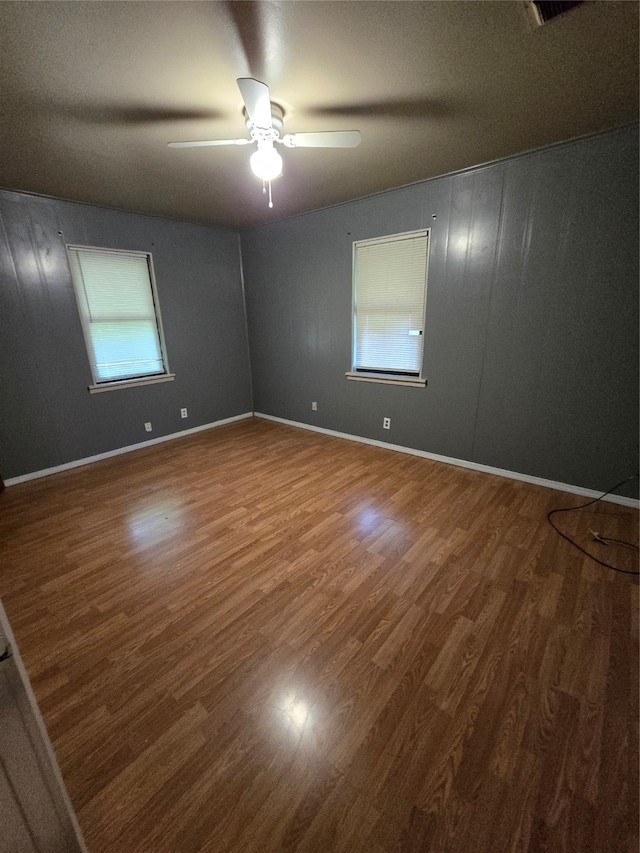 empty room with plenty of natural light, ceiling fan, and hardwood / wood-style flooring