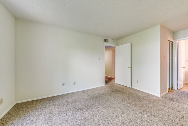 carpeted empty room featuring a textured ceiling