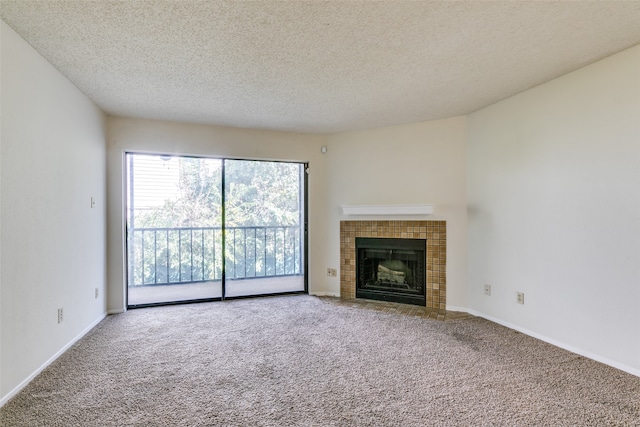 unfurnished living room with a tiled fireplace, carpet, and a textured ceiling