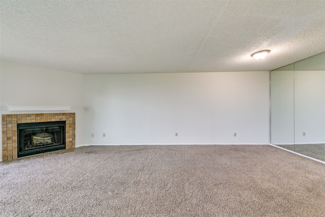 unfurnished living room featuring a tile fireplace, carpet, and a textured ceiling