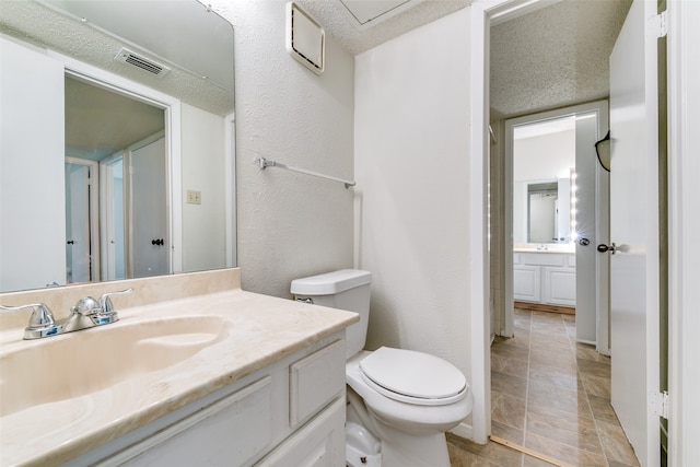 bathroom featuring vanity, toilet, and a textured ceiling