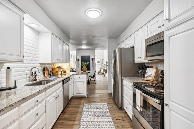 kitchen featuring white cabinetry, dark hardwood / wood-style flooring, light stone counters, stainless steel appliances, and sink