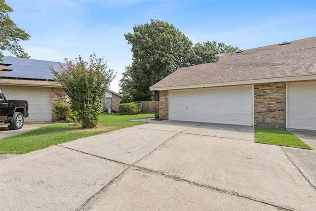 view of property exterior featuring a garage, a yard, and solar panels