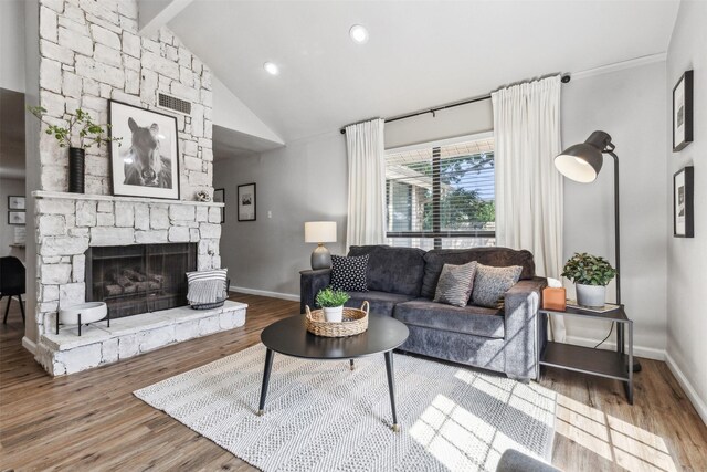 living room featuring a stone fireplace, beamed ceiling, hardwood / wood-style floors, and high vaulted ceiling