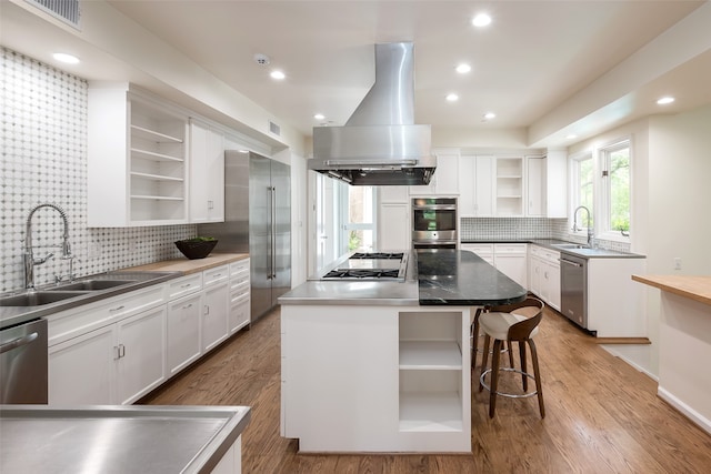 kitchen featuring tasteful backsplash, white cabinets, stainless steel appliances, a kitchen island, and island exhaust hood