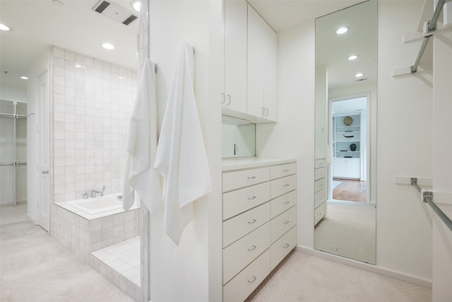 bathroom with a relaxing tiled tub and hardwood / wood-style flooring