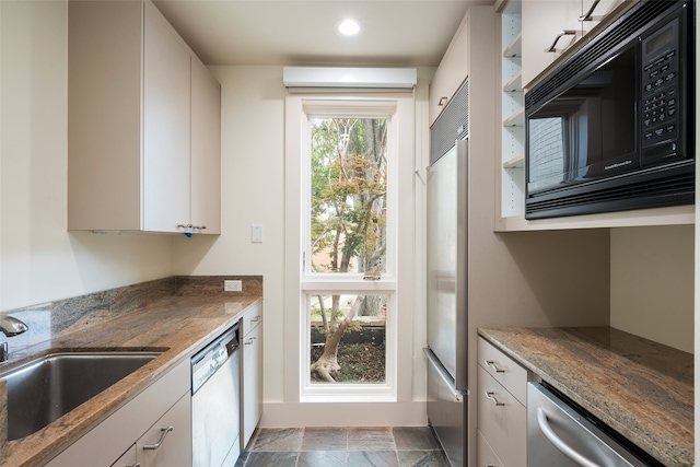 kitchen with built in appliances, sink, light tile patterned floors, and white cabinets