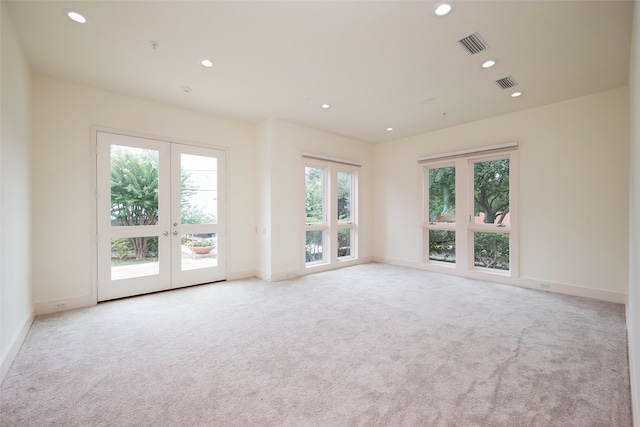 carpeted spare room featuring french doors and a wealth of natural light