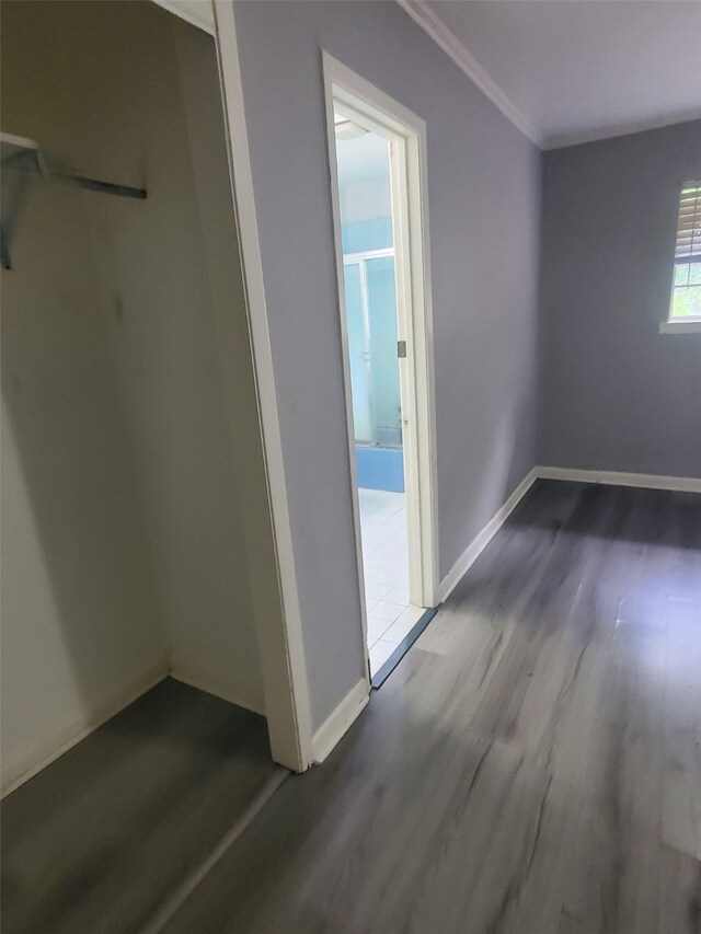 interior space featuring baseboards, wood finished floors, and ornamental molding