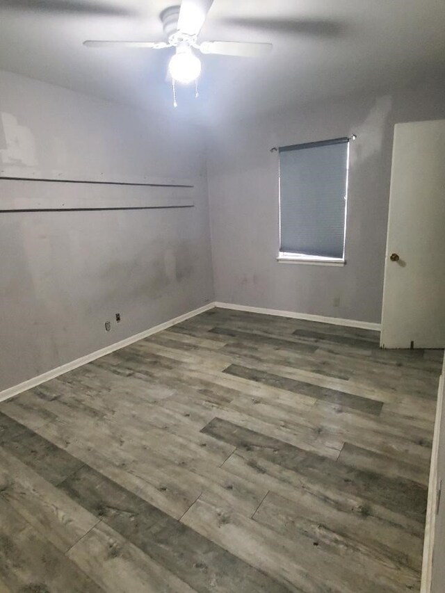 spare room featuring wood finished floors, baseboards, and ceiling fan