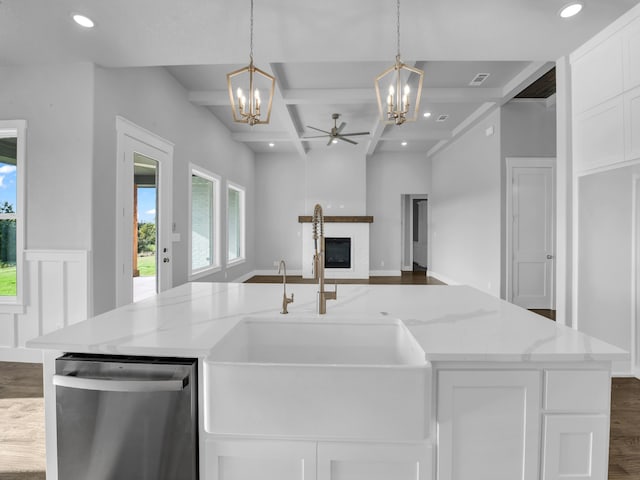 kitchen featuring pendant lighting, coffered ceiling, stainless steel dishwasher, light stone countertops, and beam ceiling