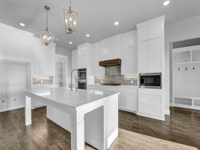 kitchen featuring white cabinetry, an island with sink, decorative light fixtures, and appliances with stainless steel finishes