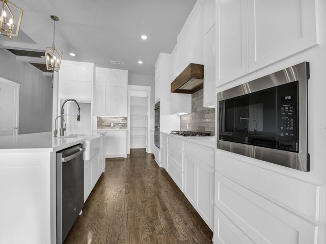 kitchen with white cabinets, appliances with stainless steel finishes, decorative light fixtures, and decorative backsplash