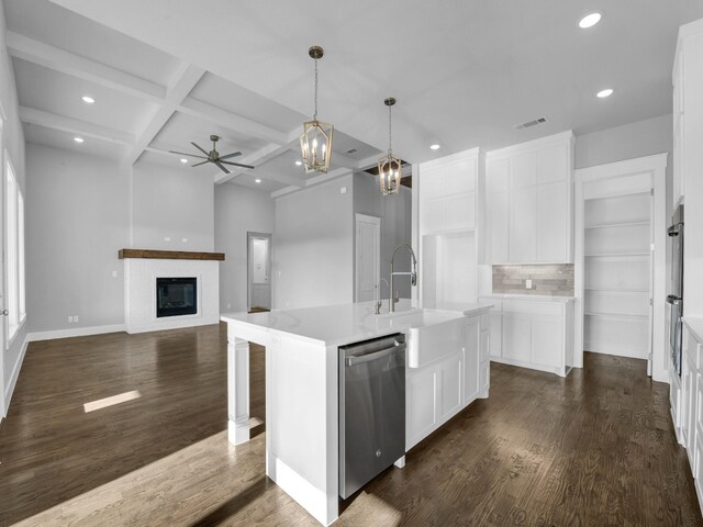 kitchen featuring coffered ceiling, white cabinets, stainless steel dishwasher, an island with sink, and beam ceiling