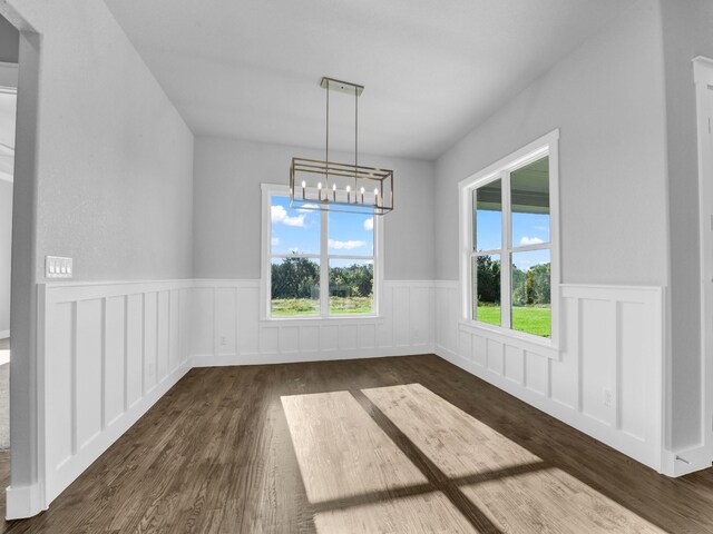 unfurnished dining area featuring dark hardwood / wood-style floors and a chandelier