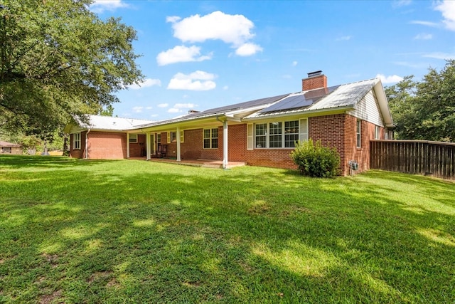 back of property featuring a yard and solar panels