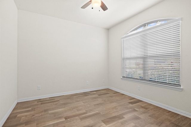 empty room featuring light wood finished floors, a ceiling fan, and baseboards