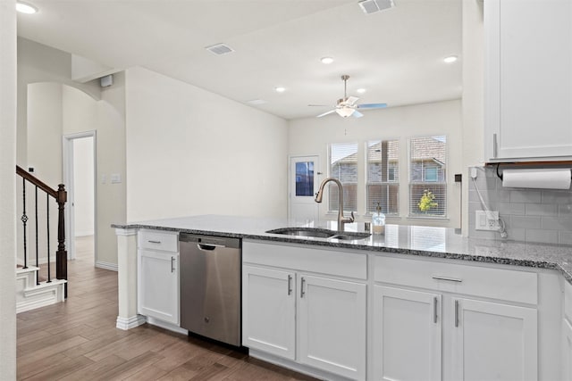 kitchen with a sink, stone countertops, white cabinetry, and stainless steel dishwasher