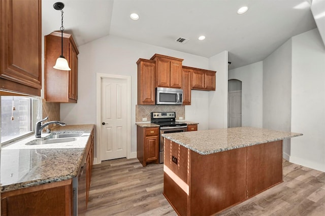 kitchen featuring hanging light fixtures, sink, stainless steel appliances, and a center island