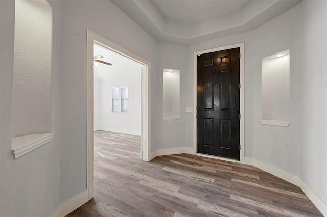 entrance foyer with ceiling fan, a tray ceiling, and hardwood / wood-style floors