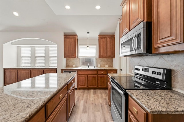 kitchen featuring appliances with stainless steel finishes, light stone counters, and light hardwood / wood-style flooring