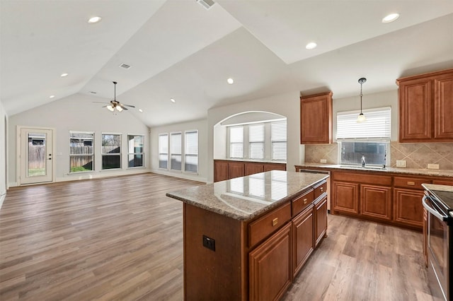 kitchen with decorative light fixtures, ceiling fan, vaulted ceiling, a center island, and stainless steel electric stove