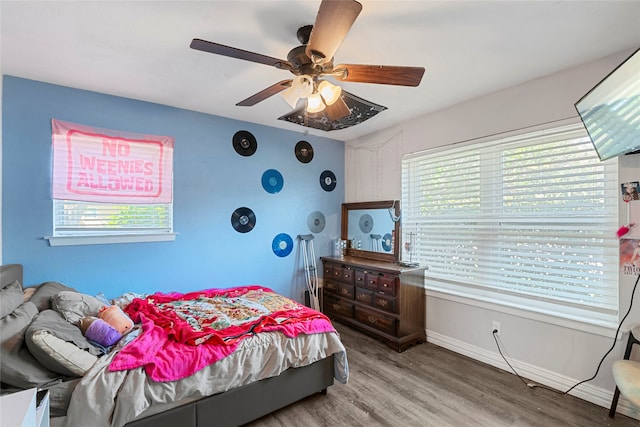 bedroom with multiple windows, wood-type flooring, and ceiling fan