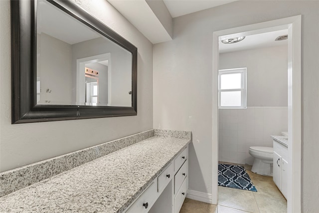 bathroom featuring tile patterned flooring, tile walls, toilet, and vanity