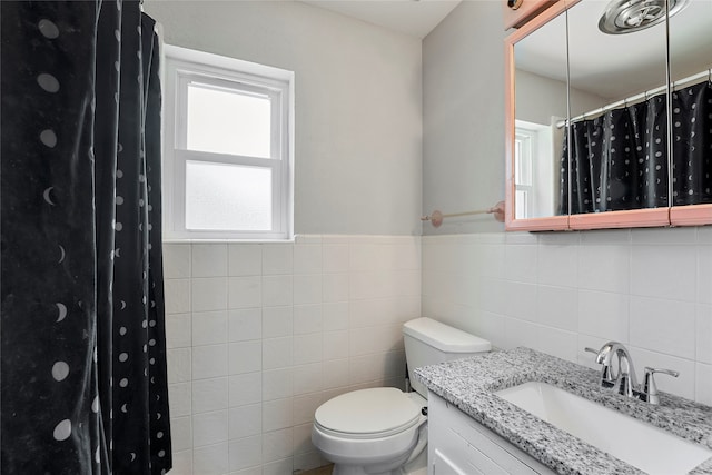 bathroom with vanity, toilet, decorative backsplash, and tile walls